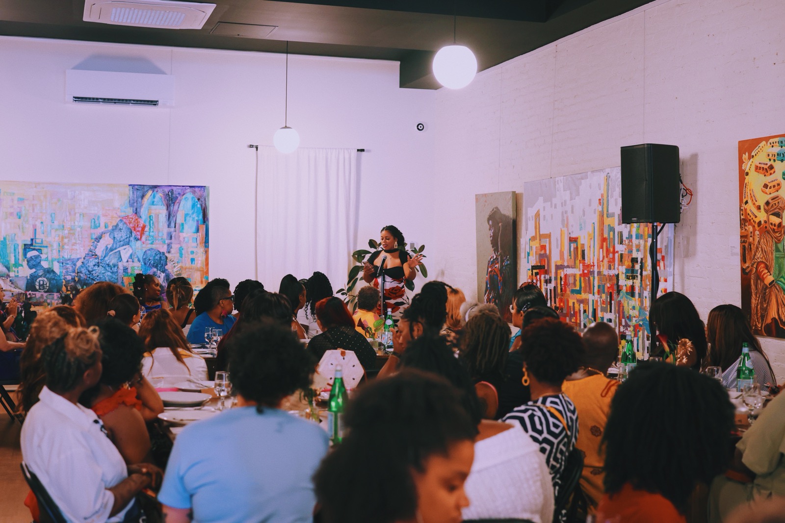 A speaker addressing guests in the gallery