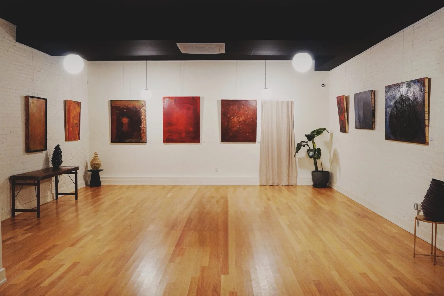 The gallery with clean exhibition walls and globe pendant lighting